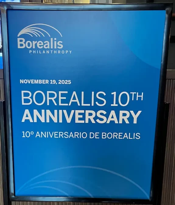 An example of a translated welcome sign: a framed blue placard reading 'November 19, 2025, Borealis 10th Anniversary' in English above '10 Aniversario de Borealis' in Spanish.