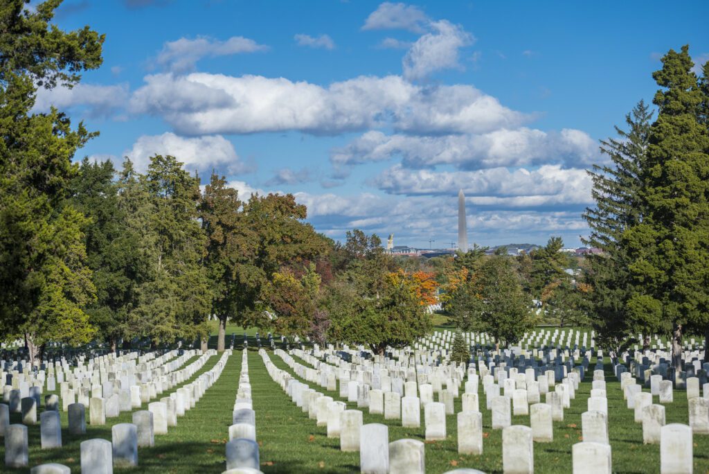 Rows of white headstones across the sloping lawns of Arlington National Cemetery.