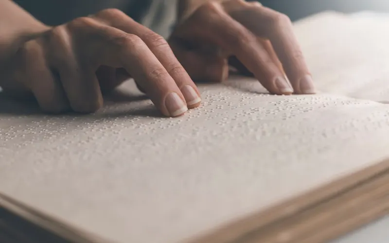 Hands reading an embossed Braille page