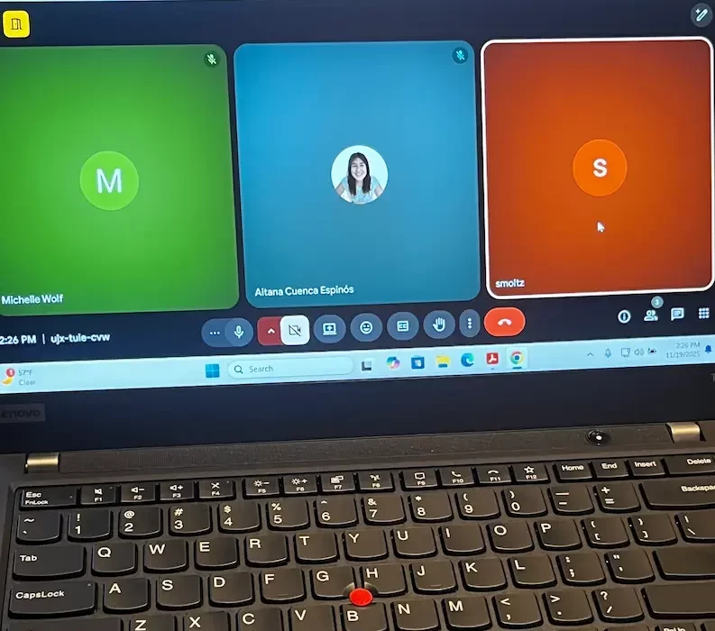 Behind the scenes: a laptop on the tech table shows a video call linking the remote captioner, the ICS captioning manager, and the room feed for the session being captioned.
