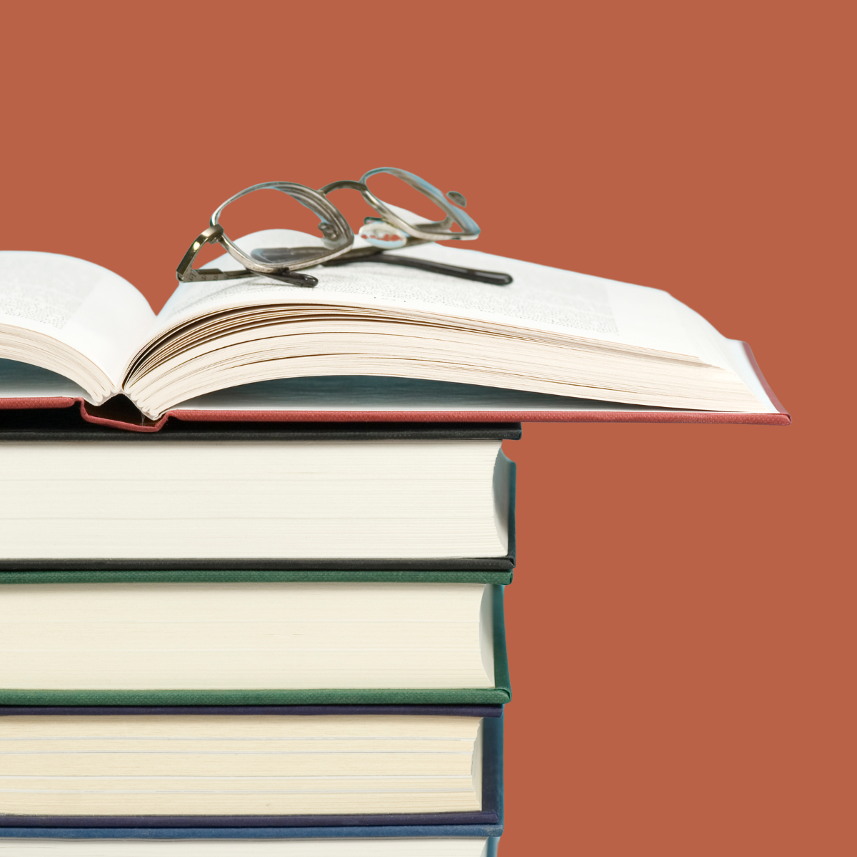 Stack of books with reading glasses resting on the open top book