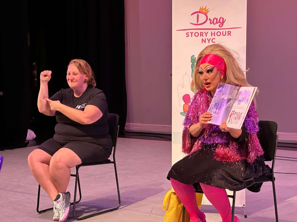 Shelby, an ASL interpreter and ICS co-founder, is interpreting for a drag queen who is reading a book to an audience. At the "Drag Story Hour NYC."