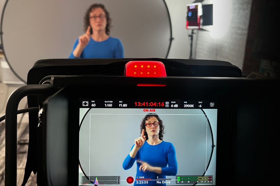 Interpreter signing on camera in front of studio lighting