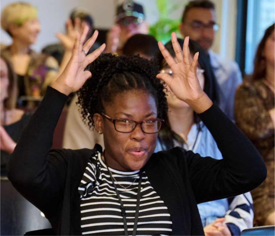 Mid-sign with both hands raised, interpreting in front of an audience