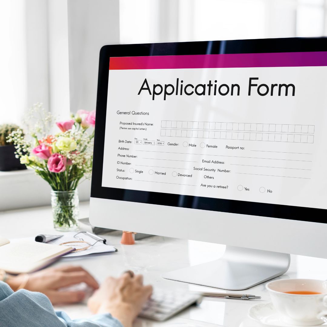 Hands type at a keyboard in front of an on-screen application form.