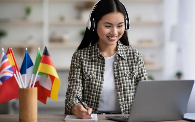 A translator working at a laptop with international flags beside it