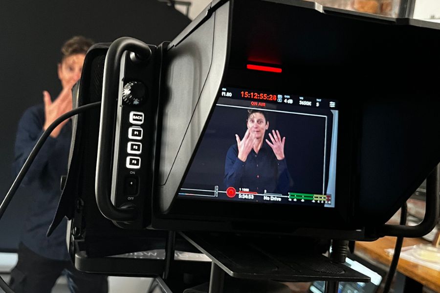 Camera monitor showing an interpreter signing on a studio set